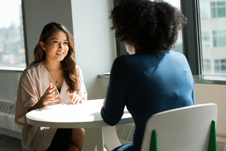Duas pessoas conversando à mesa em um ambiente acolhedor