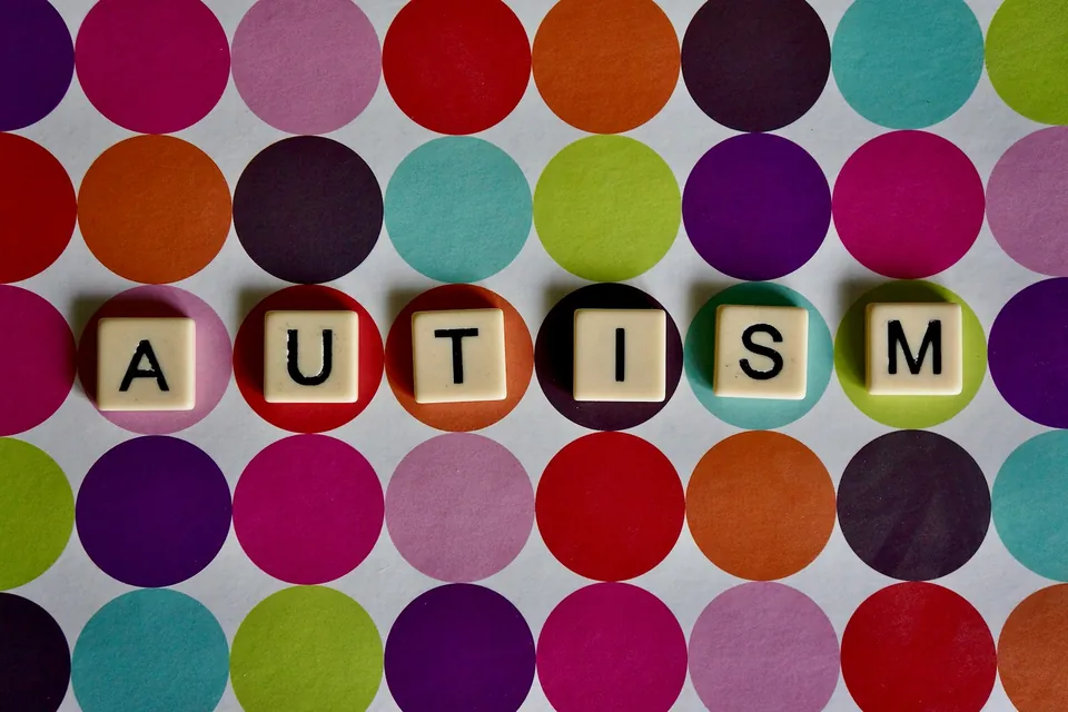 Blocos com a palavra AUTISM sobre um fundo de círculos coloridos